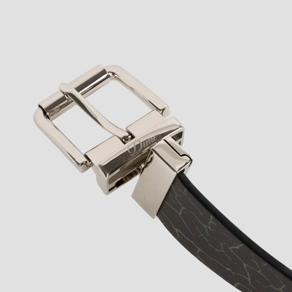 Ceinture Reversible Leather Dime MTL – ceinture cuir noir et craquelé avec boucle logo, réversible, tailles S-M et L-XL. Zoom sur l'inscription de la boucle