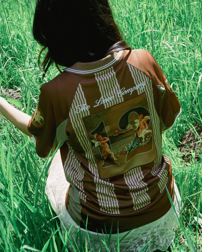 Angel Jersey marron The Loose Company, maillot football revisité streetwear avec patches brodés et logo. Skate Mons Saint-Ghislain, porté par une fille.
