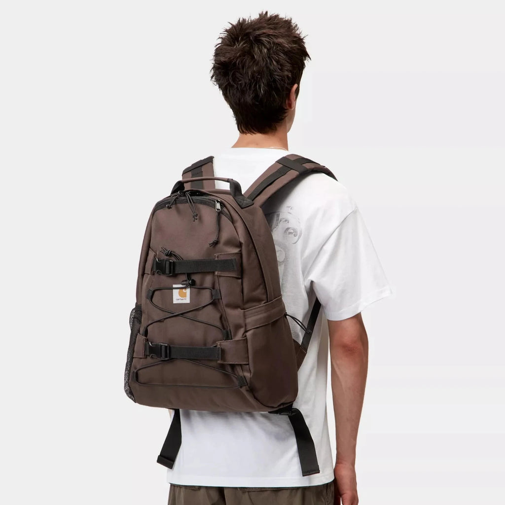 Sac à dos Carhartt WIP Kickflip Palisander – 24,8 L en polyester recyclé déperlant, poches multiples et sangles skate – dispo à Mons. Vue de dos porté par un mannequin