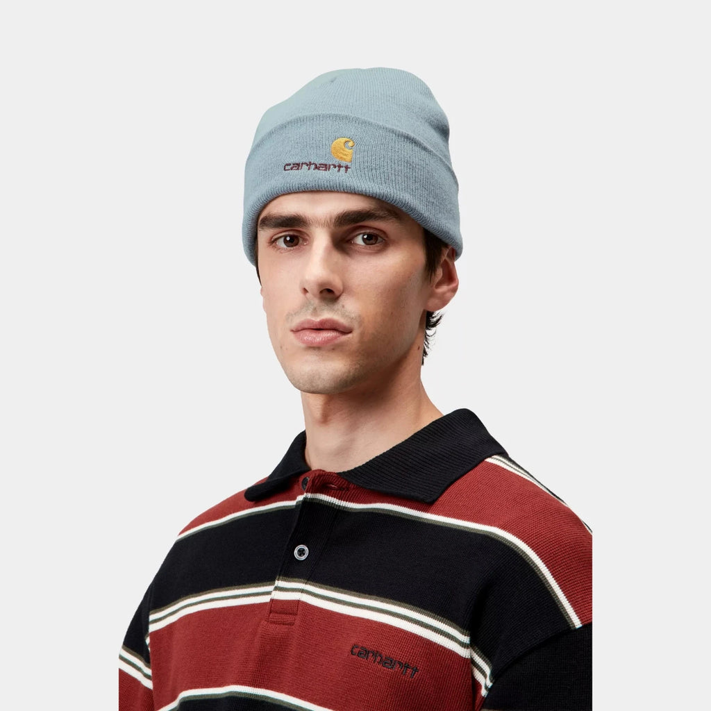 Bonnet Carhartt WIP American Script en polyester recyclé, avec revers et logo brodé bicolore – dispo à Mons. Porté par un mannequin