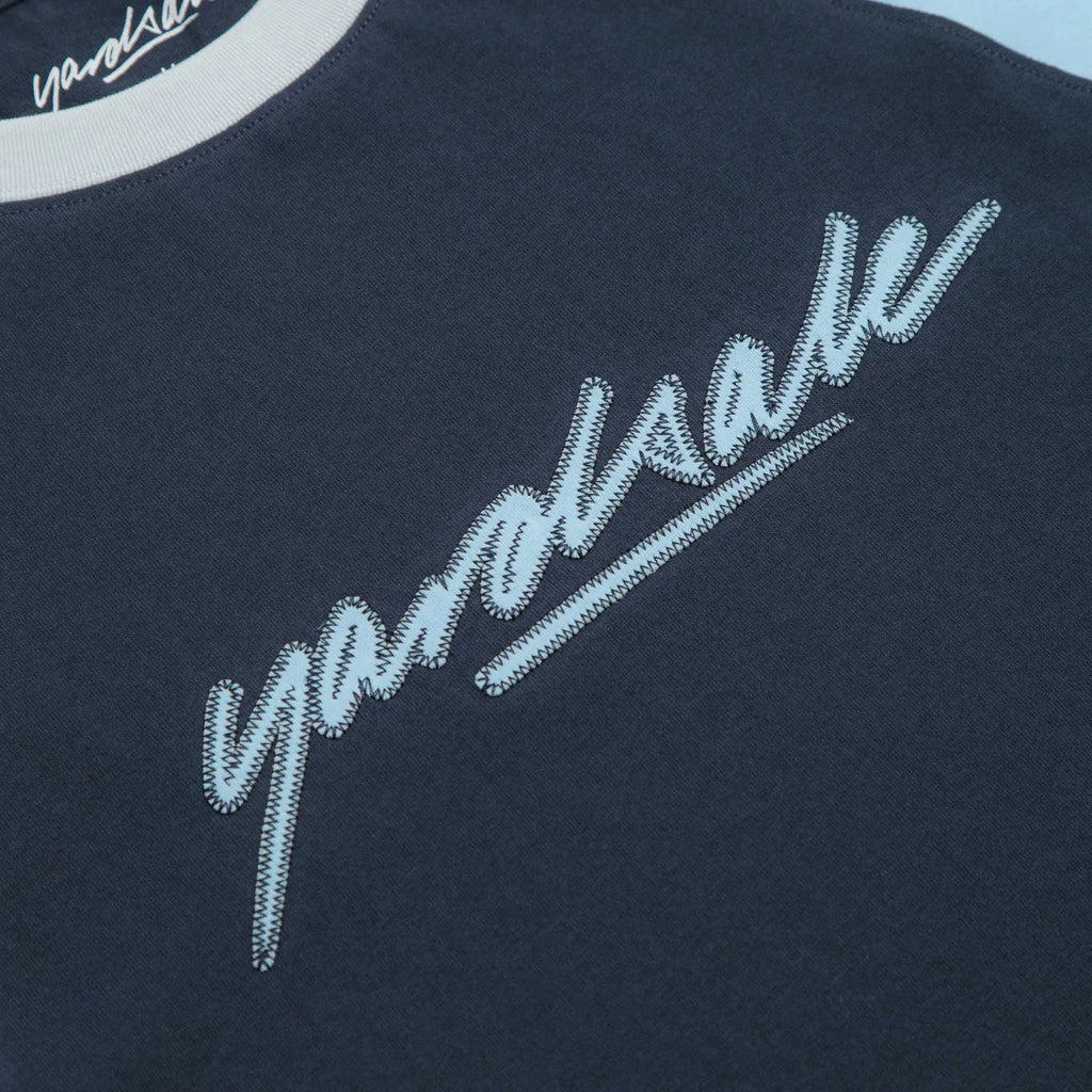 T-shirt skate Yardsale Daze Bleu en coton avec manches raglan et logo brodé – disponible à Mons chez Yagö Skateshop. Zoom sur le logo du milieu brodé